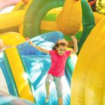 Happy little girl having lots of fun on a jumping castle during sliding.