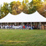 white outdoor tent full of tables and people seated