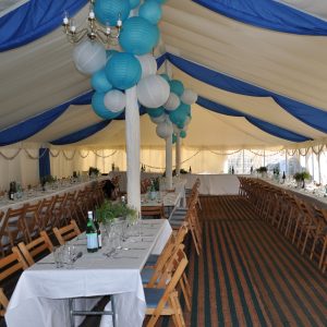 Wedding reception held in a huge tent decorated with balloons and blue and white curtains.